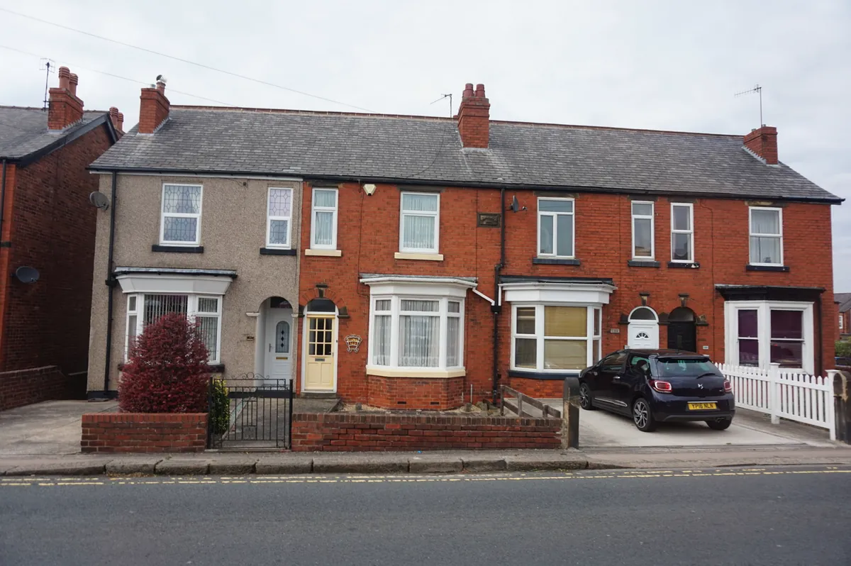 A row of red-brick and rendered bay-windowed houses with small front gardens on Hasland Road in Chesterfield